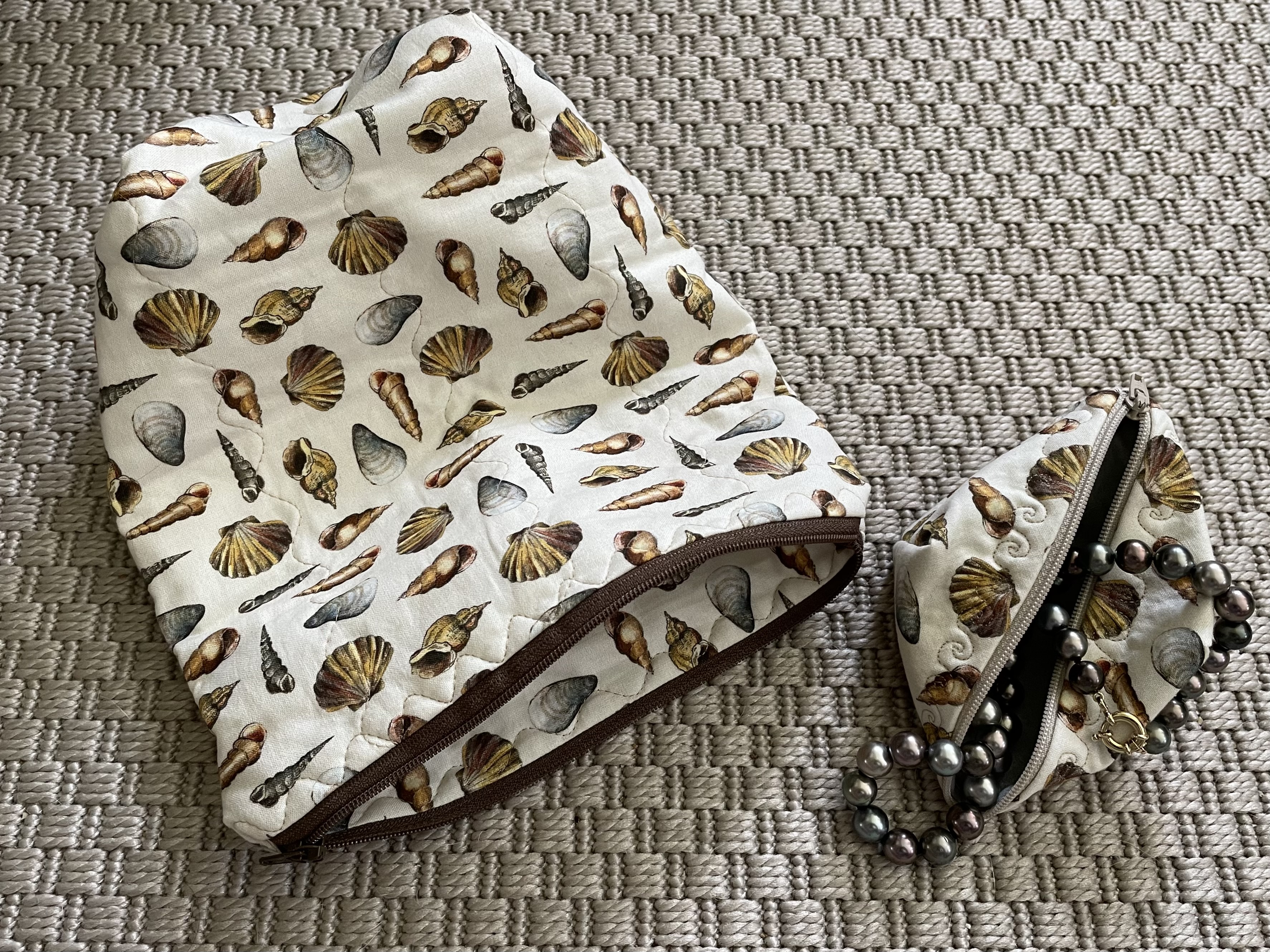 seashell fabric has little waves by the zipper on the smaller pouch, and the flower fabric has little bees by the zipper! The pearl strands are both Kamoka