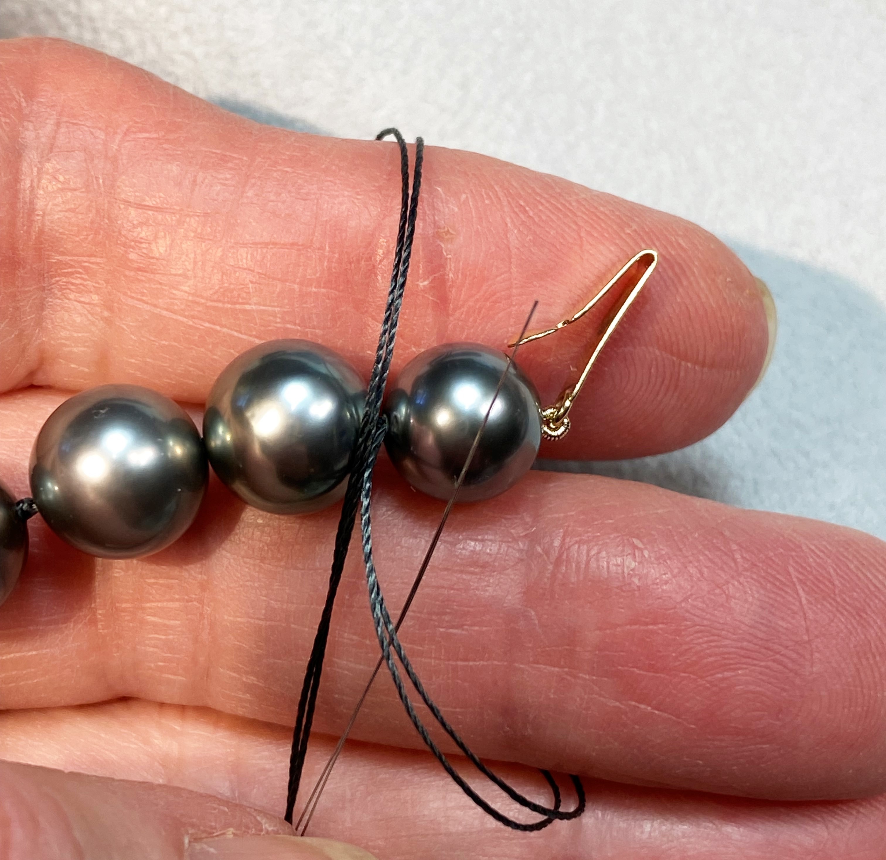 Making the final knots ~ hold in my hand, thread goes down through middle fingers,over index finger and up through to make a half hitch (needle points toward the end!)  Keep threads from twisting, Tighten between pearls. String through 2nd pearl, repeat knot.